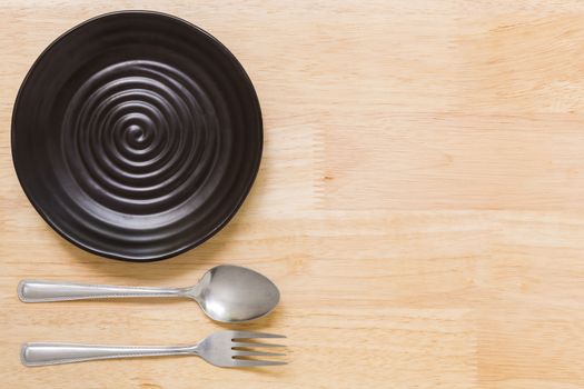 Empty plate with spoon and fork on table background.