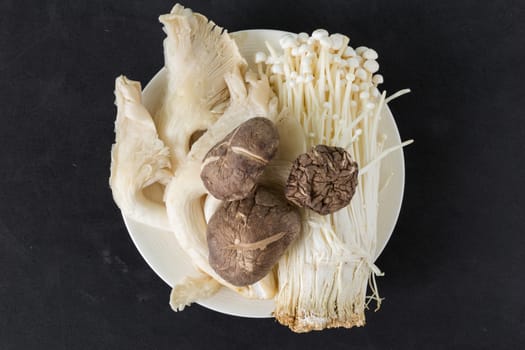 Various kinds of mushroom in a plate on black background.