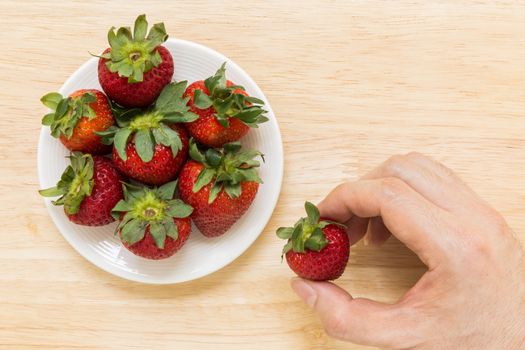Strawberry in white plate on wooden background