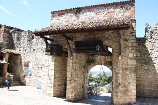 Stone wall with merlons and drawbridge gate of medieval castle of Brescia in north Italy