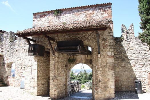 Stone wall with merlons and drawbridge gate of medieval castle of Brescia in north Italy