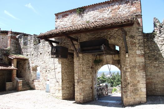 Stone wall with merlons and drawbridge gate of medieval castle of Brescia in north Italy