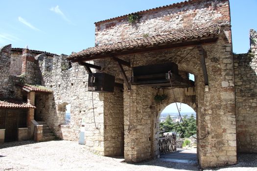 Stone wall with merlons and drawbridge gate of medieval castle of Brescia in north Italy