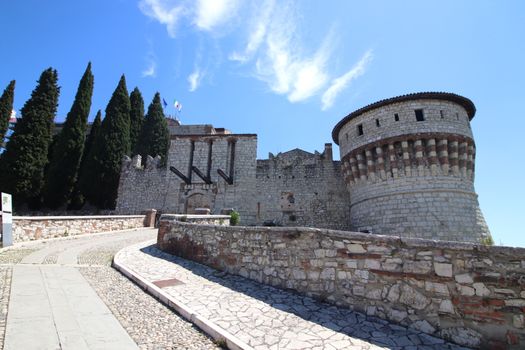 Stone wall with merlons and drawbridge gate of medieval castle of Brescia in north Italy