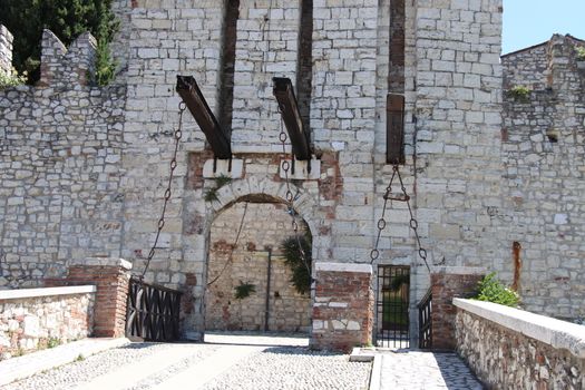 Stone wall with merlons and drawbridge gate of medieval castle of Brescia in north Italy