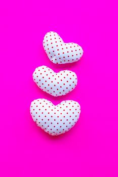 Red dots on white heart shape, Valentine's hearts on pink background, Top view with copy space