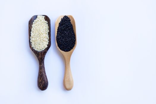 Black and white sesame seeds on wooden spoon, white background. Copy space
