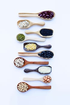 Different beans, legumes on wooden spoon on white background.