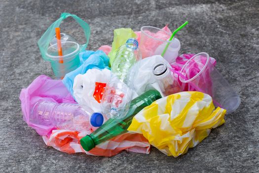 Colorful plastic waste, bags, cups, bottles, straws on cement floor background