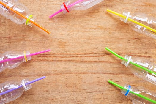 Plastic waste, Plastic bottles with straws on wooden background.