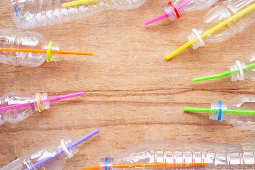 Plastic waste, Plastic bottles with straws on wooden background.