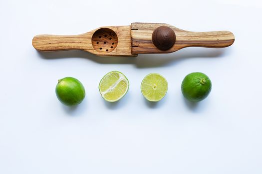 Limes with wooden lime squeezer on white background