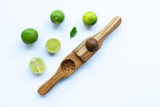 Limes with wooden lime squeezer on white background