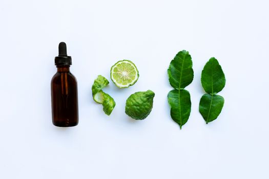 Bottle of essential oil and  fesh bergamot fruit with leaves isolated on white background.