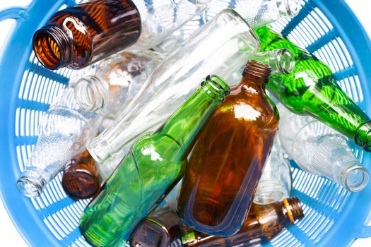 Glass bottles in blue waste basket.