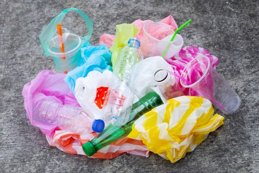 Colorful plastic waste, bags, cups, bottles, straws on cement floor background