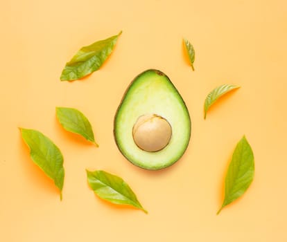 Avocado  with leaves on orange background. Top view