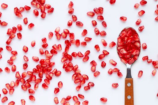 Spoon with pomegranate seeds isolated on white background.
