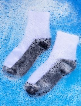 Dirty socks soaking in powder detergent water dissolution. Laundry concept