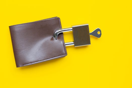 Wallet with padlock and key on yellow background. Copy space
