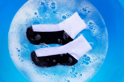 Dirty socks soaking in powder detergent water dissolution. Laundry concept