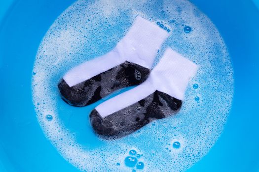 Dirty socks soaking in powder detergent water dissolution. Laundry concept