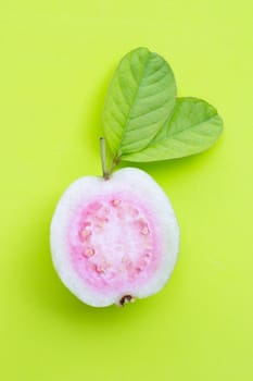 Top view of fresh ripe guava and slices with leaves on green background.