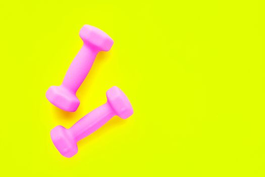 Top view of pink dumbbells isolated on yellow background. Copy space