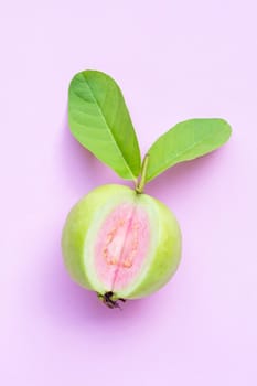 Top view of fresh ripe guava with leaves on pink background.