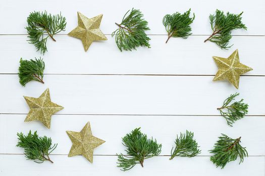 Merry Christmas and Happy Holidays, Christmas composition frame made of golden stars, pine branches  on white wooden background. Top view