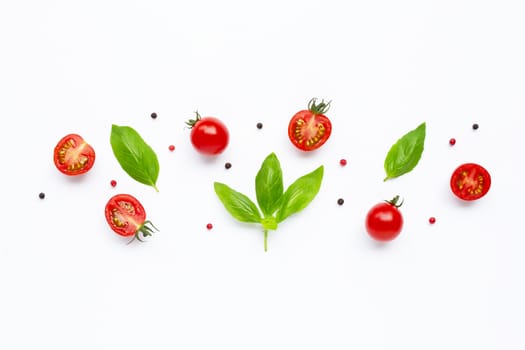 Fresh  cherry tomatoes with basil leaves and different type of peppercorns on white background. Top view