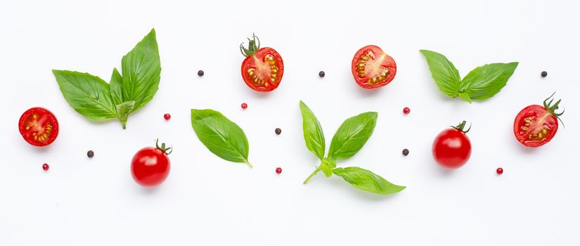 Fresh  cherry tomatoes with basil leaves and different type of peppercorns on white background. Top view