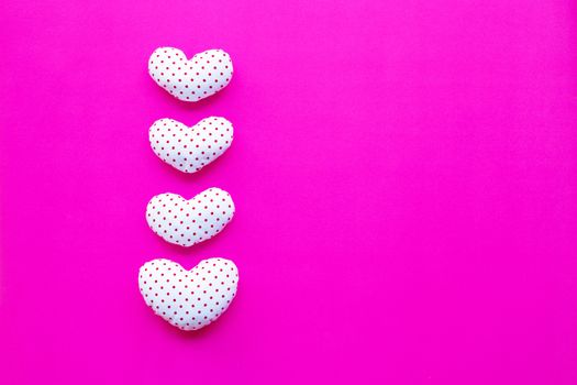 Red dots on white heart shape, Valentine's hearts on pink background, Top view with copy space