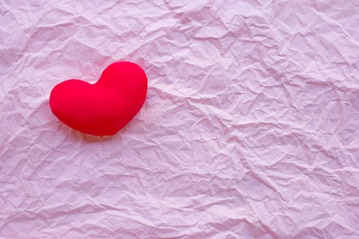 Valentine's heart on pink crumpled paper background. Top view
