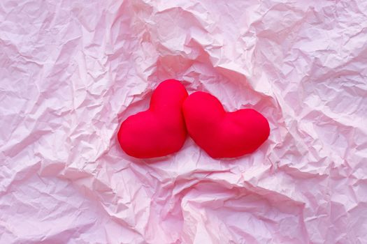Valentine's hearts on pink crumpled paper background. Top view