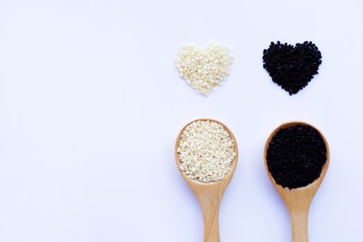 Black and white sesame seeds on wooden spoon, white background. Copy space
