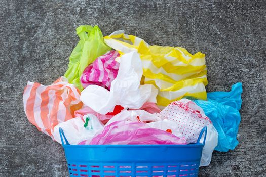 Colorful plastic bags with trash basket on cement floor background. 