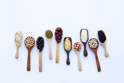 Different beans, legumes on wooden spoon on white background.