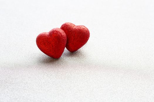 The red heart shapes on silver glitter paper background in love concept for valentines day. Copy space