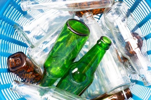 Glass bottles in blue waste basket.