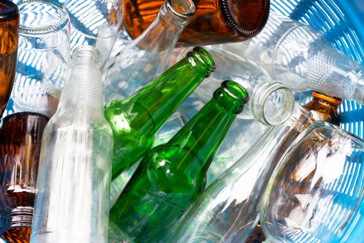 Glass bottles in blue waste basket.