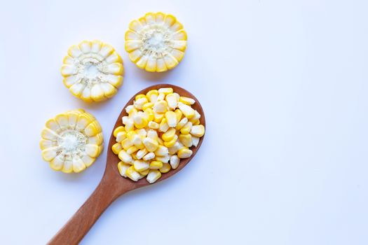 Corn seeds on wooden spoon and ripe corn cobs on on white background