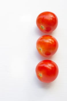 Tomatoes on white wooden background.