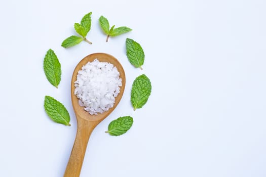 Salt in wooden spoon with fresh mint on white background