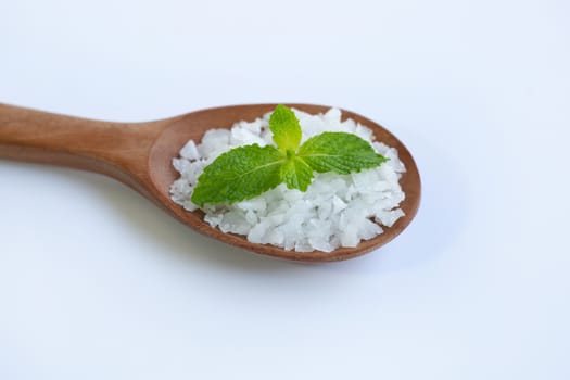 Salt in wooden spoon with fresh mint on white background