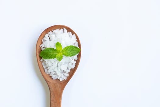 Salt in wooden spoon with fresh mint on white background