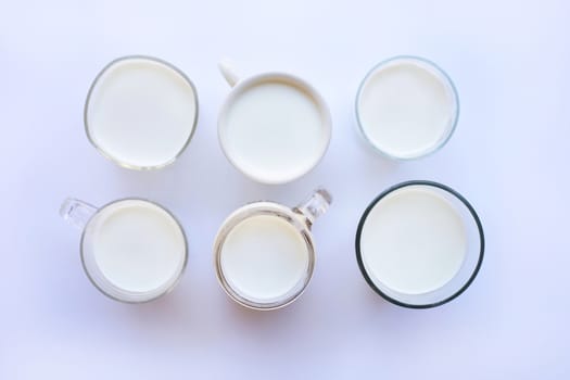 Cup and glass of milk on white background