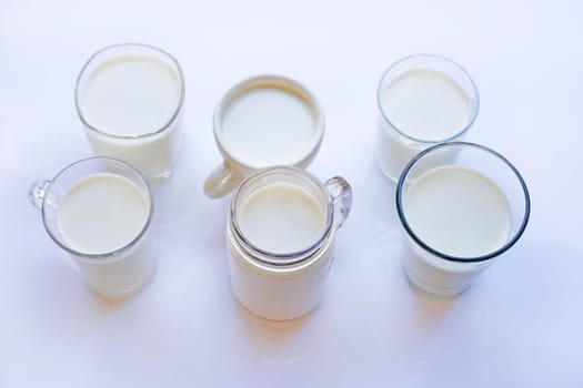 Cup and glass of milk on white background