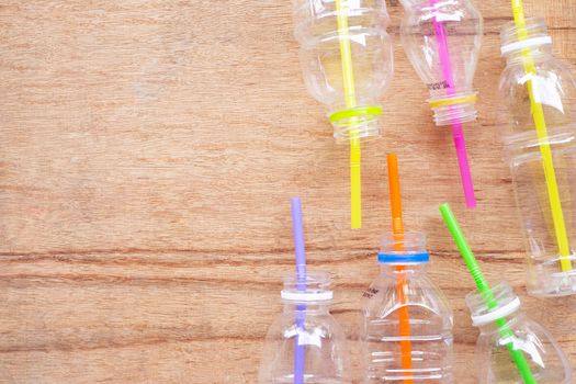 Plastic waste, Plastic bottles with straws on wooden background.