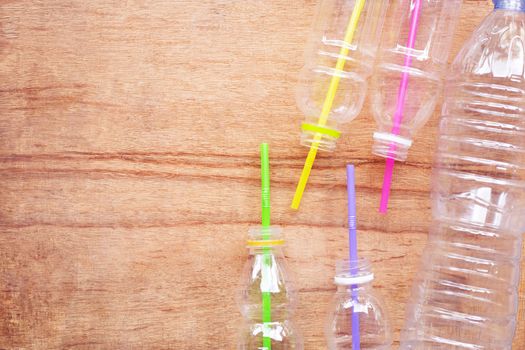 Plastic waste, Plastic bottles with straws on wooden background.